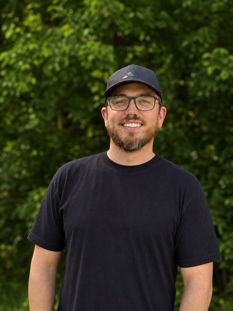 Kyle, founder of Simple Signal, smiling outdoors in a cap and glasses